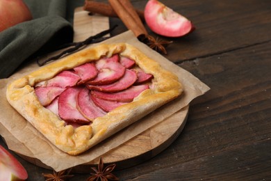 Photo of Delicious galette with apples, spices and fruit on wooden table, closeup. Space for text