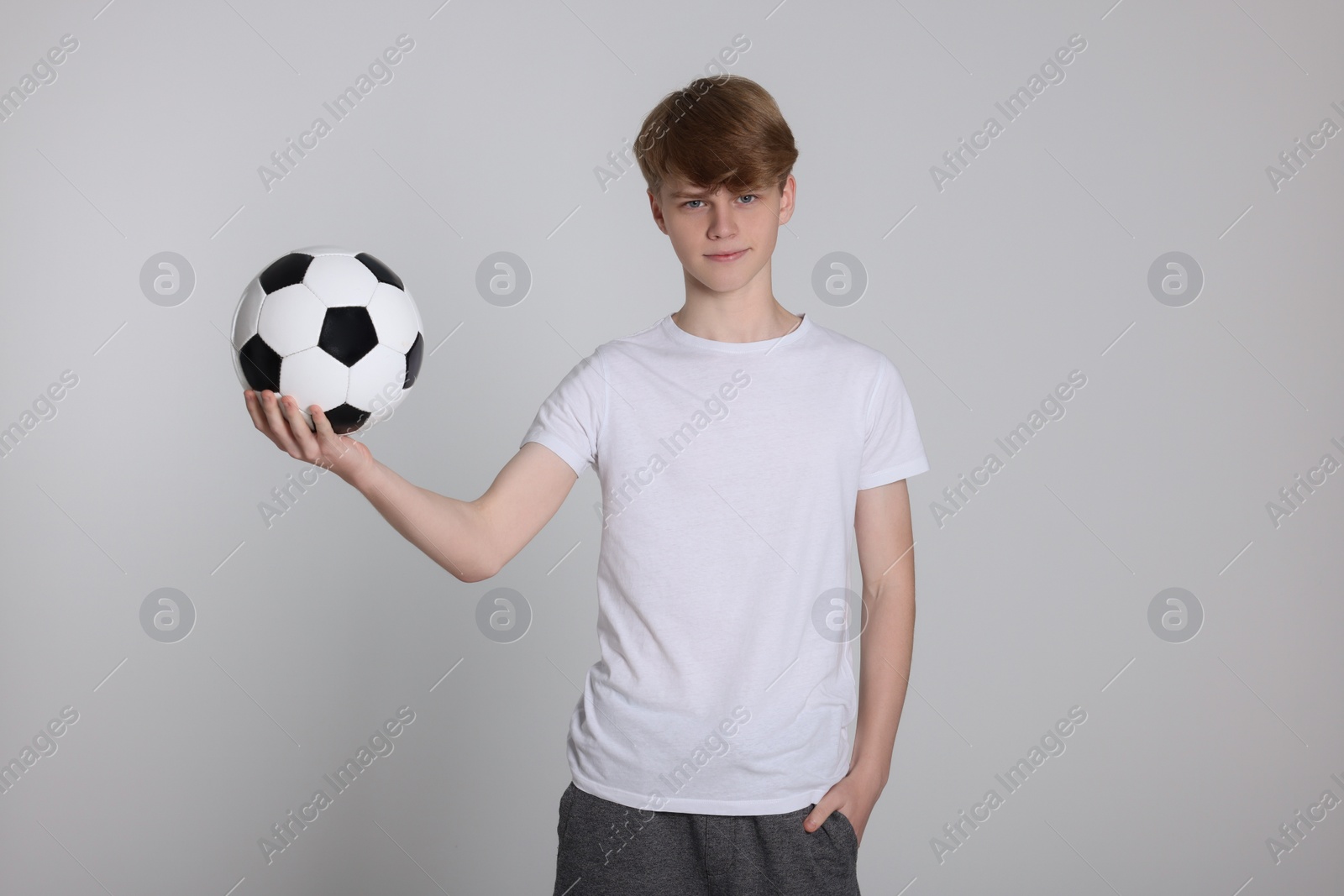 Photo of Teenage boy with soccer ball on light grey background