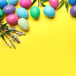 Photo of Bright painted eggs and pussy willows on yellow background, flat lay with space for text. Happy Easter