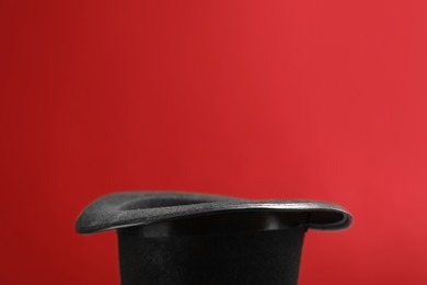 Photo of Black magician's hat on red background, closeup. Space for text