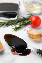 Photo of Organic balsamic vinegar and cooking ingredients on white table, closeup