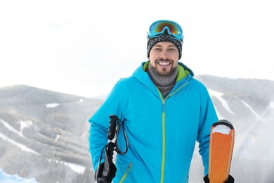 Man with ski equipment spending winter vacation in mountains