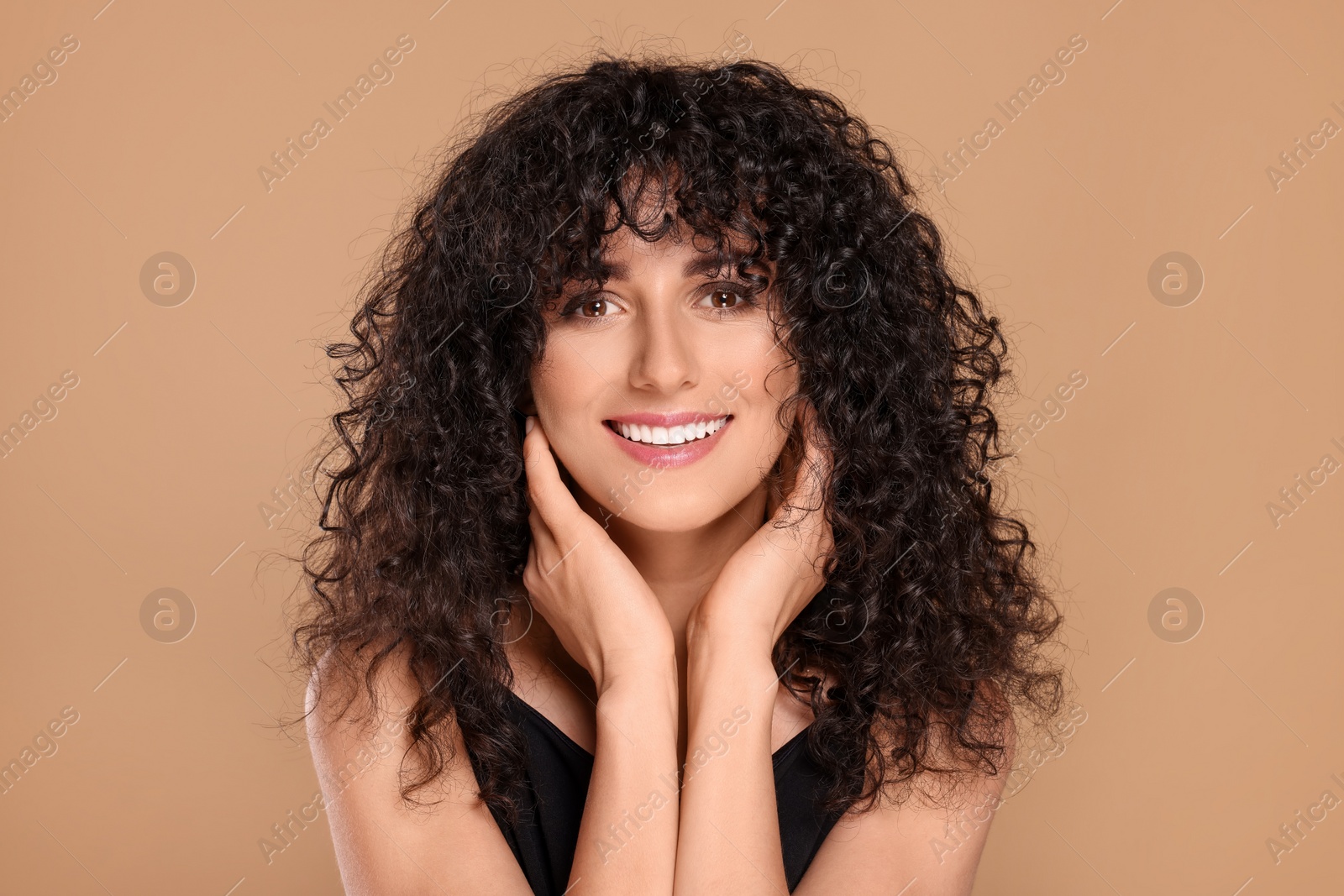 Photo of Beautiful young woman with long curly hair on beige background