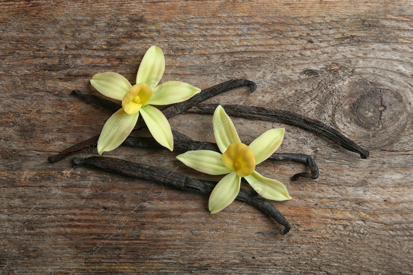 Photo of Flat lay composition with vanilla sticks and flowers on wooden background