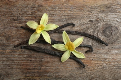 Flat lay composition with vanilla sticks and flowers on wooden background