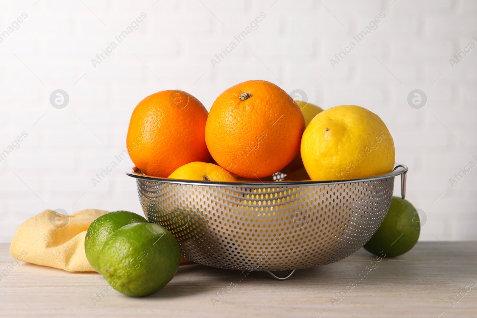 Photo of Different fresh fruits in colander on white wooden table