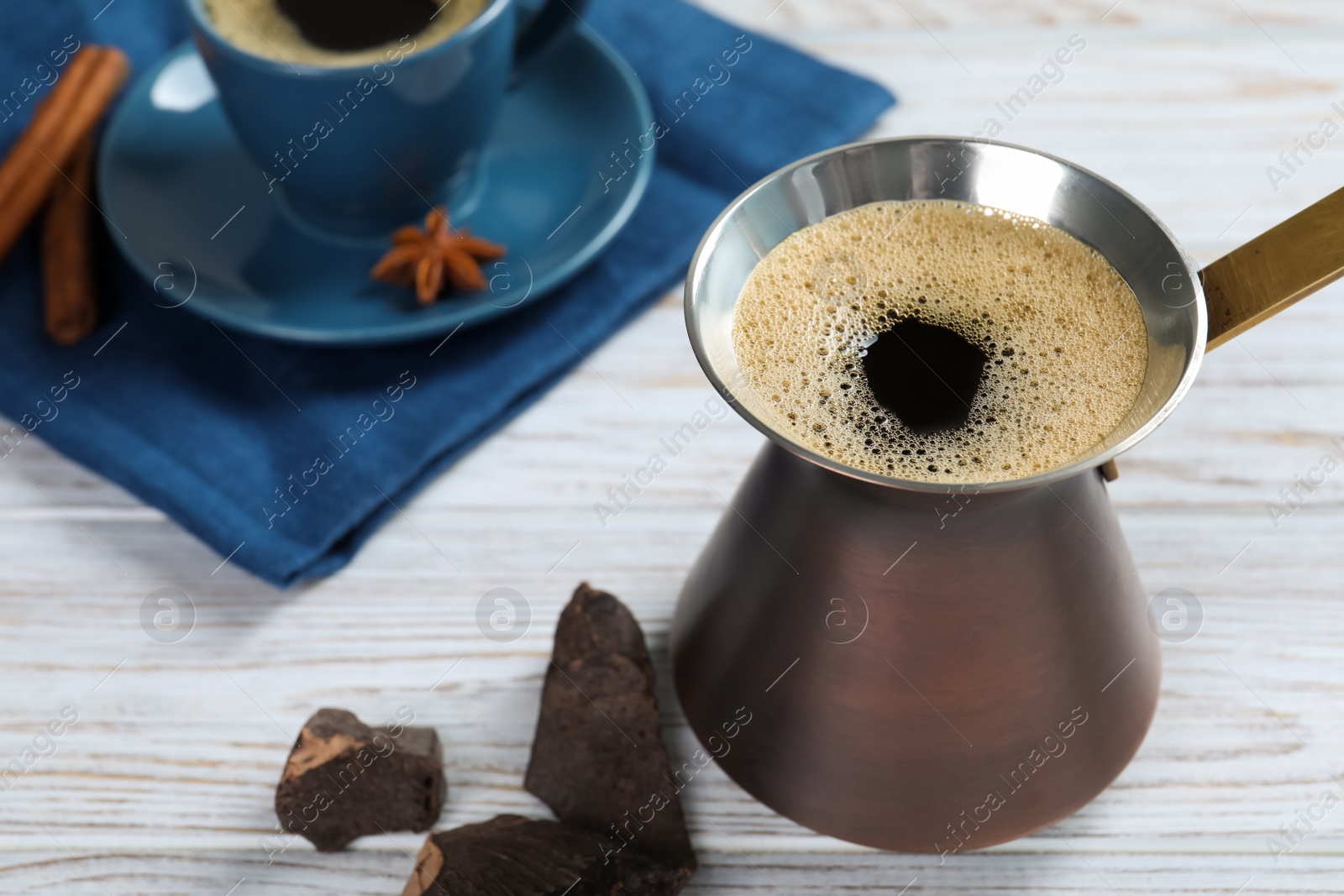 Photo of Hot turkish coffee pot and chocolate on white wooden table, space for text