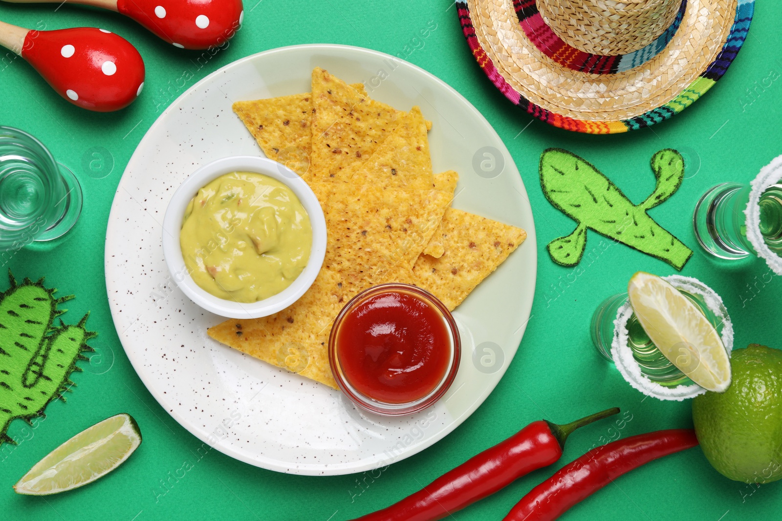 Photo of Flat lay composition with nachos chips and Mexican sombrero hat on green background