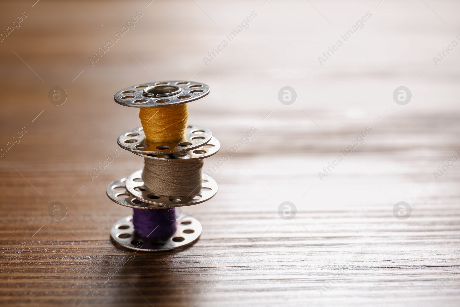 Photo of Spools with threads for tailoring on wooden background