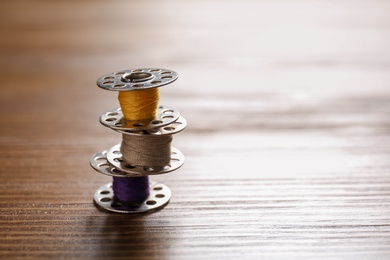 Photo of Spools with threads for tailoring on wooden background