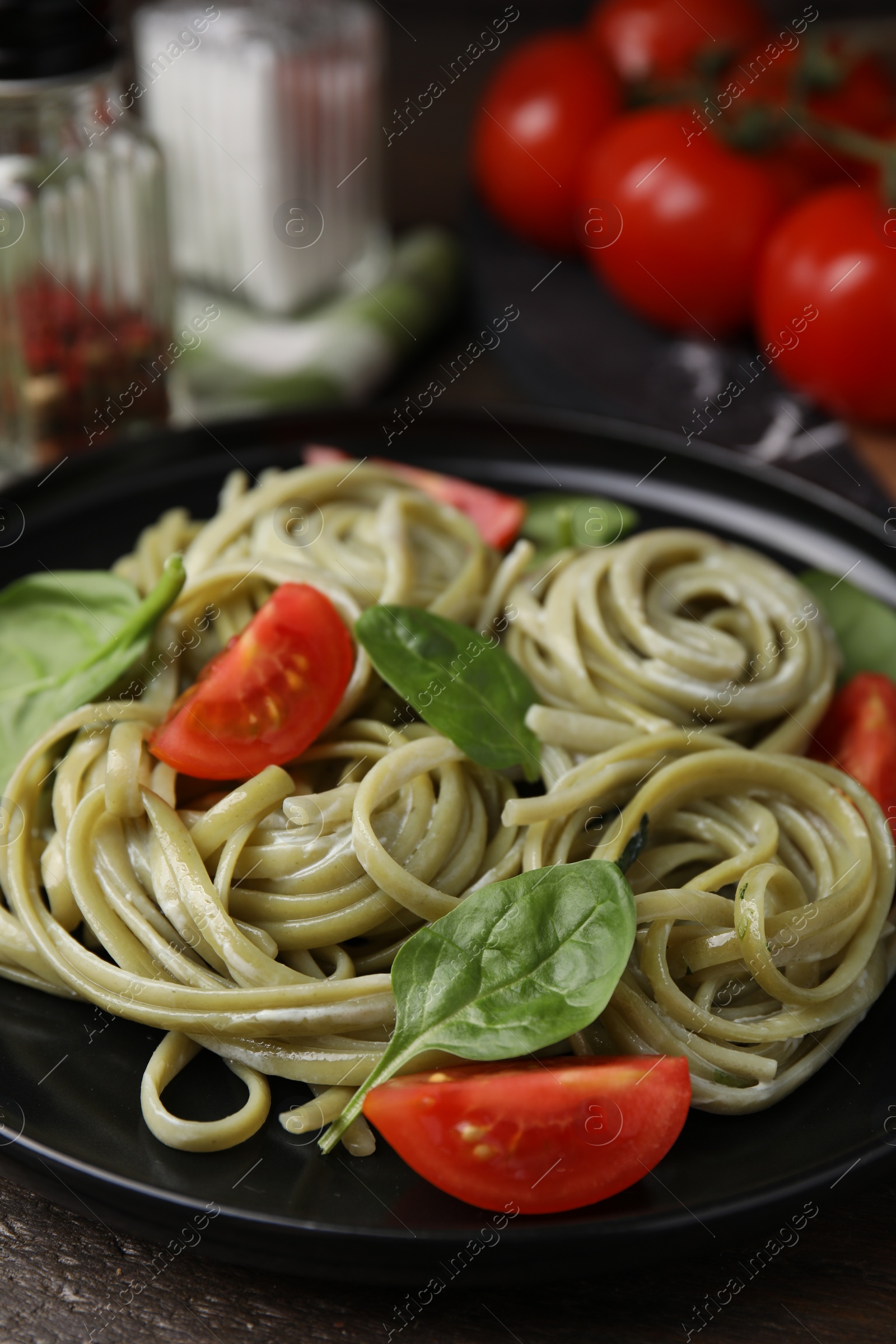 Photo of Tasty pasta with spinach and tomatoes on table, closeup