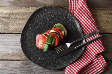 Photo of Delicious ratatouille served with basil on wooden table, top view