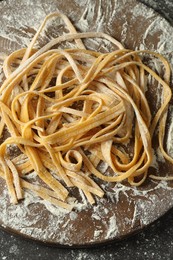 Photo of Uncooked homemade pasta on dark table, above view