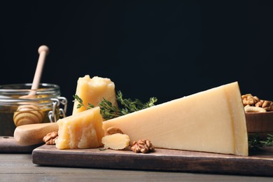 Photo of Delicious parmesan cheese served with honey, walnuts and thyme on wooden table