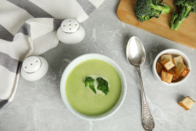 Photo of Delicious broccoli cream soup served on grey marble table, flat lay