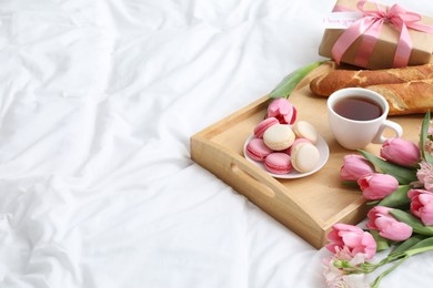 Photo of Delicious breakfast, flowers, gift box and card with phrase I Love You on bed, space for text