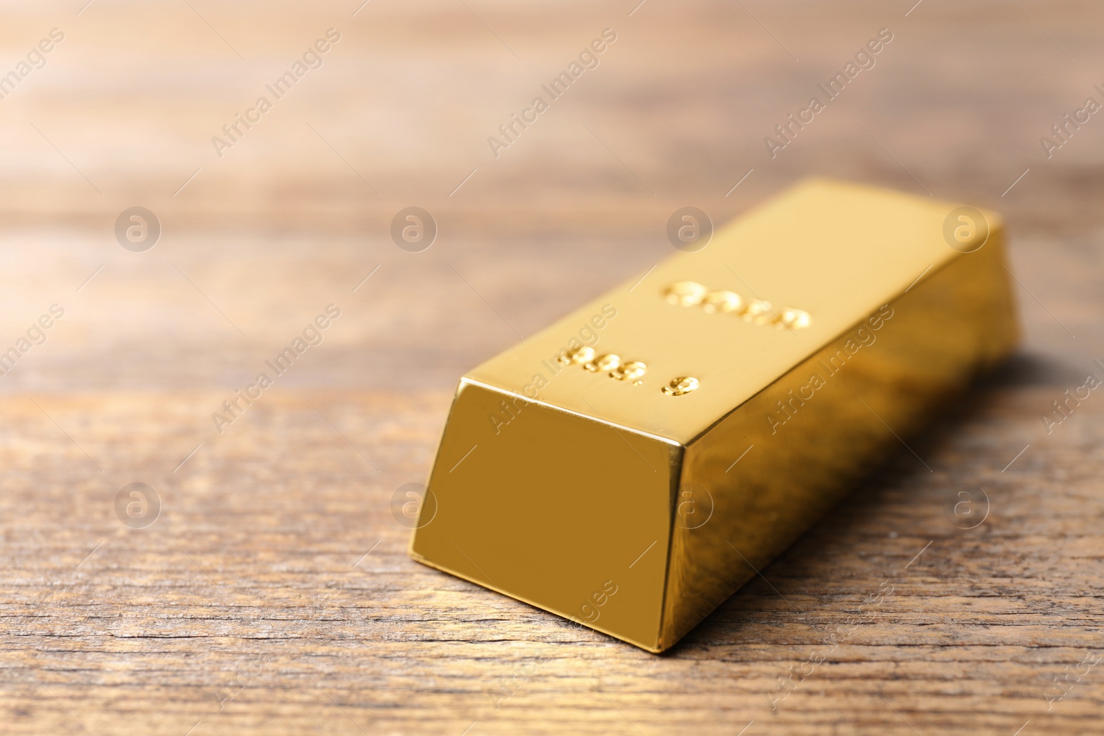 Photo of Shiny gold bar on wooden background. Space for text