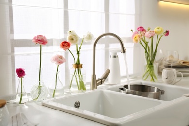 Photo of Light kitchen decorated with beautiful fresh ranunculus flowers