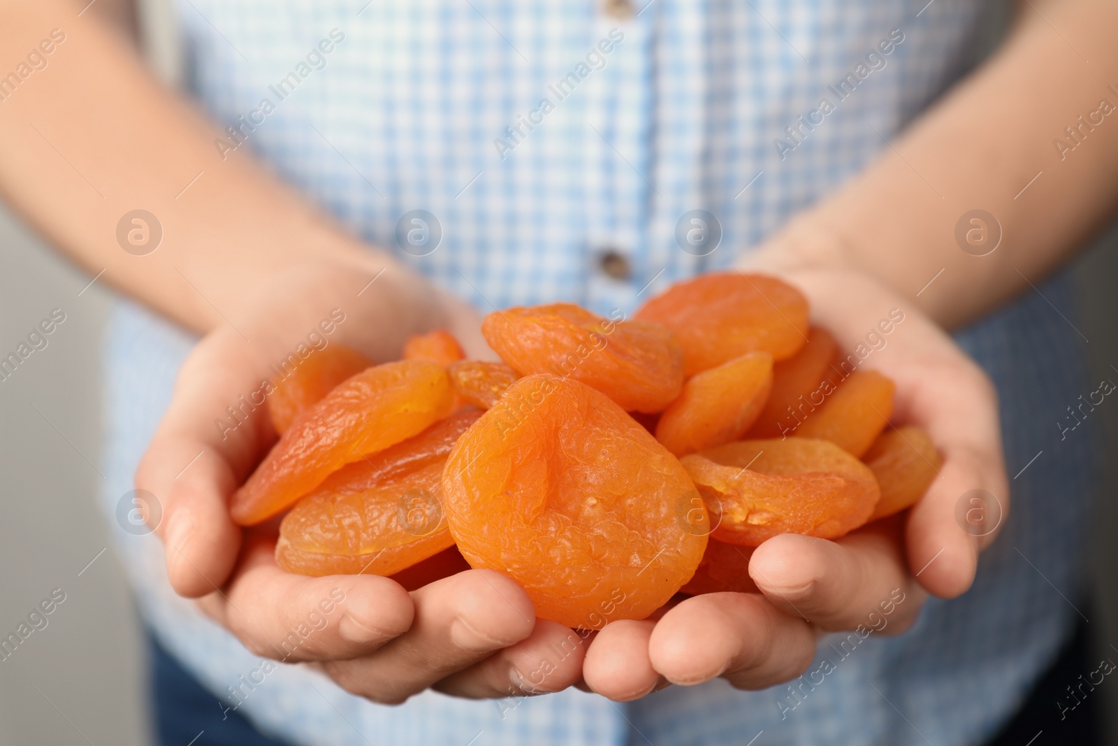 Photo of Woman holding handful of dried apricots, closeup. Healthy fruit