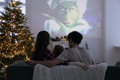Photo of Lviv, Ukraine – January 24, 2023: Family watching How The Grinch Stole Christmas movie via video projector at home, back view