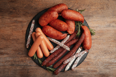 Different tasty sausages on wooden table, top view