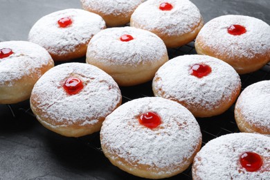 Many delicious donuts with jelly and powdered sugar on black table