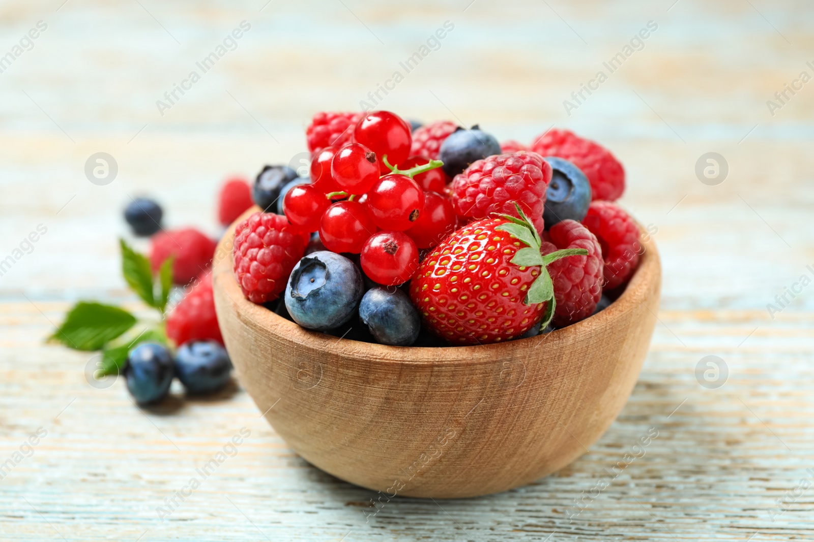 Photo of Mix of different fresh berries in bowl on wooden table