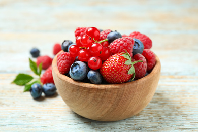 Photo of Mix of different fresh berries in bowl on wooden table