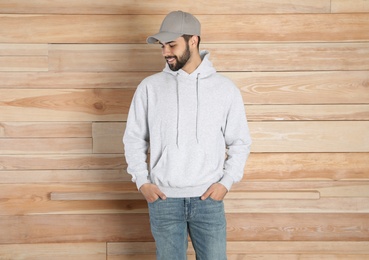 Photo of Portrait of young man in sweater at wooden wall. Mock up for design