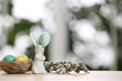 Photo of Festive composition with Easter eggs in decorative nest on table against blurred window. Space for text