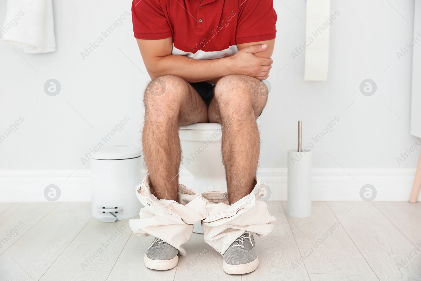 Photo of Young man suffering from diarrhea on toilet bowl at home