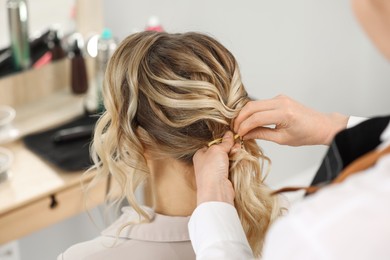 Hair styling. Professional hairdresser working with client indoors, closeup