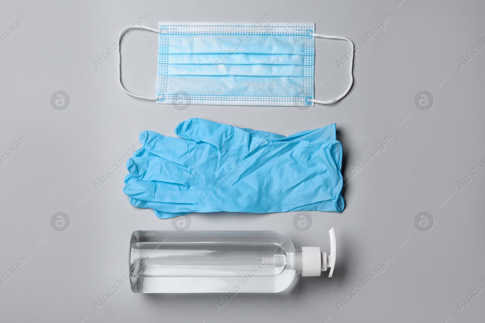 Photo of Medical gloves, mask and hand sanitizer on grey background, flat lay