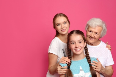 Happy sisters with their grandmother on pink background, space for text