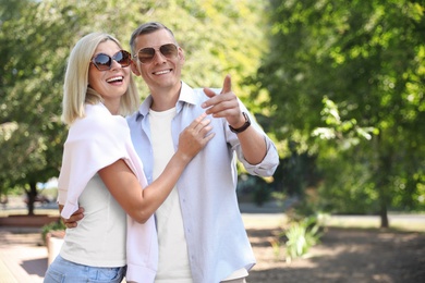 Happy couple walking along park on summer day