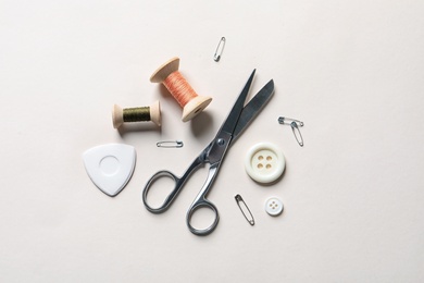 Photo of Set of tailoring accessories on light background, top view