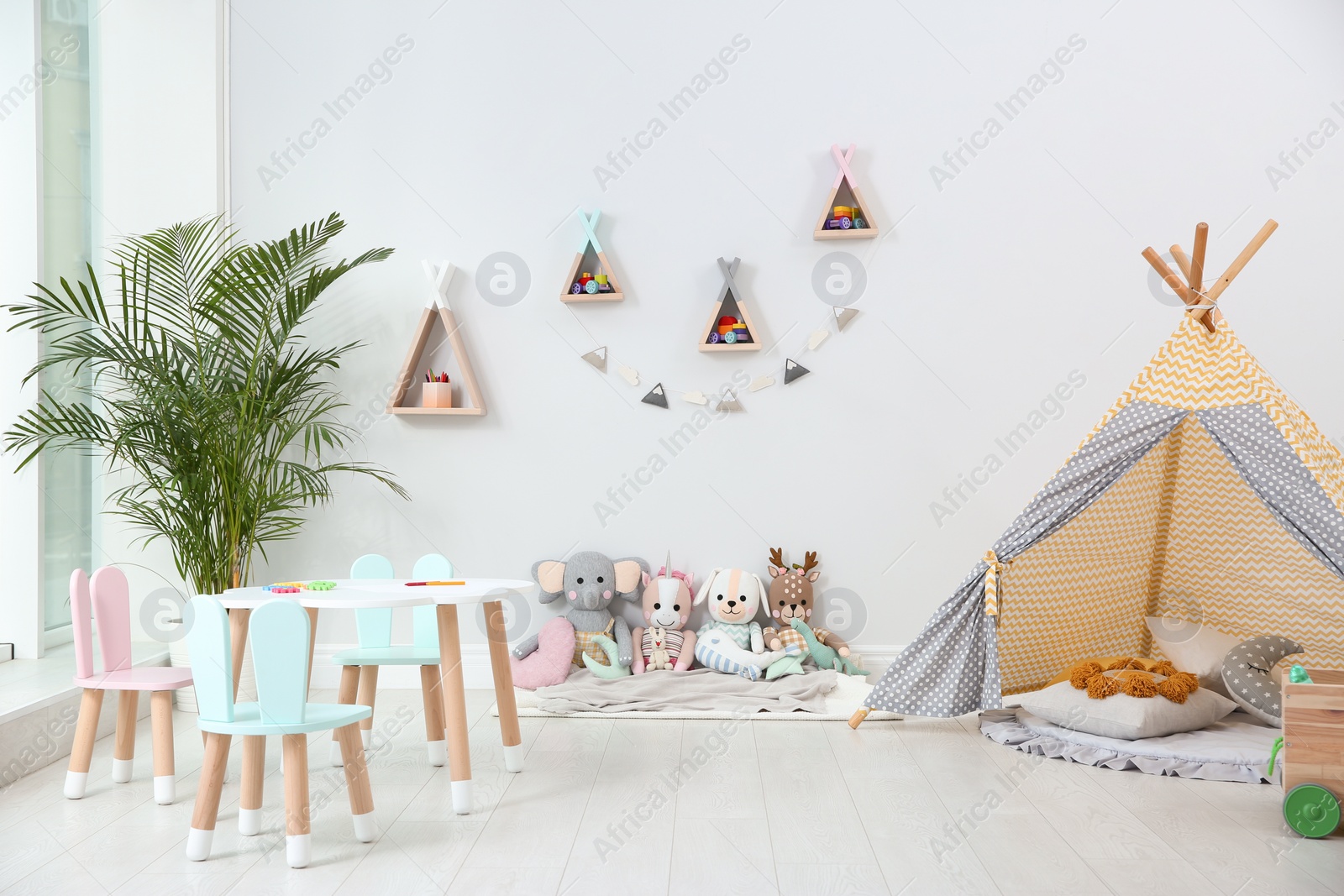 Photo of Cute children's room interior with teepee tent and little table