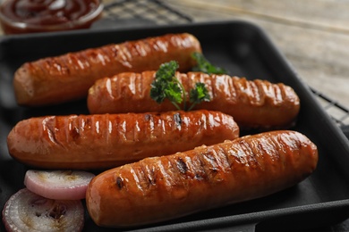 Photo of Delicious grilled sausages in grill pan, closeup. Barbecue food