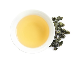 Cup of Tie Guan Yin oolong and tea leaves on white background, top view