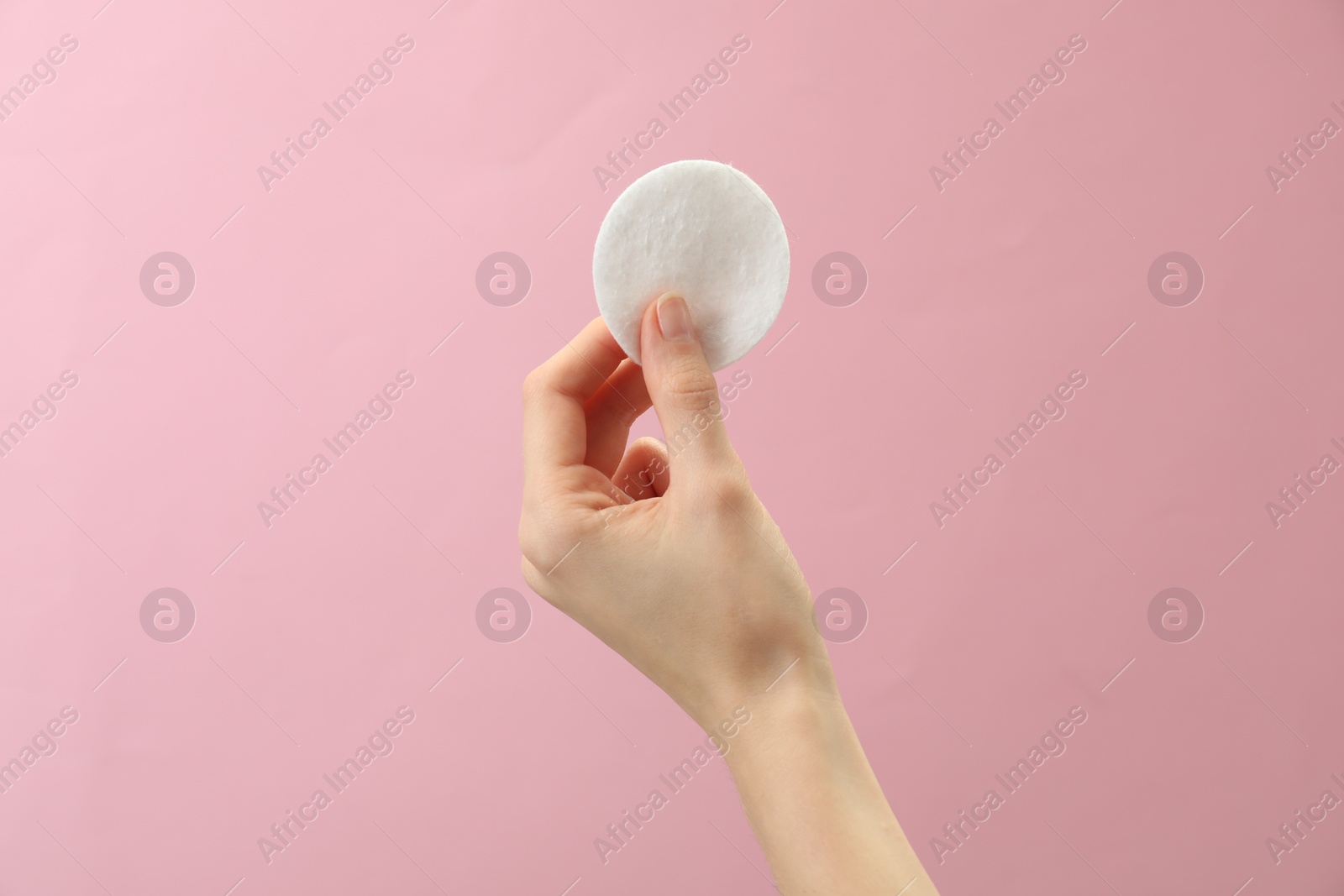 Photo of Woman holding cotton pad on pink background, closeup