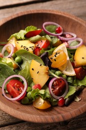 Delicious salad with peach, green peas and vegetables in bowl on wooden table, closeup
