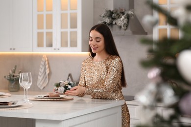 Happy woman serving table for Christmas in kitchen