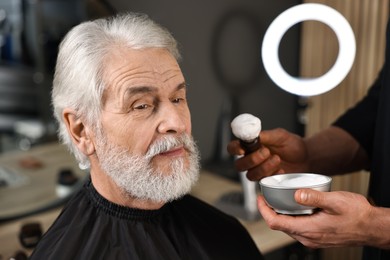 Photo of Professional barber working with client's mustache in barbershop