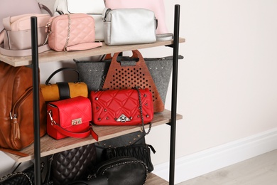 Photo of Shelving unit with stylish purses near white wall, space for text. Element of dressing room interior