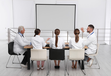 Team of doctors using video projector during conference indoors