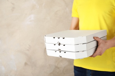 Photo of Young man with pizza boxes on color background, space for text. Food delivery service