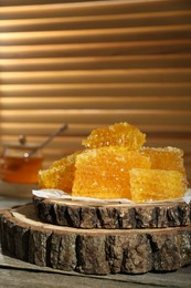 Photo of Natural honeycombs with honey on rustic table, space for text