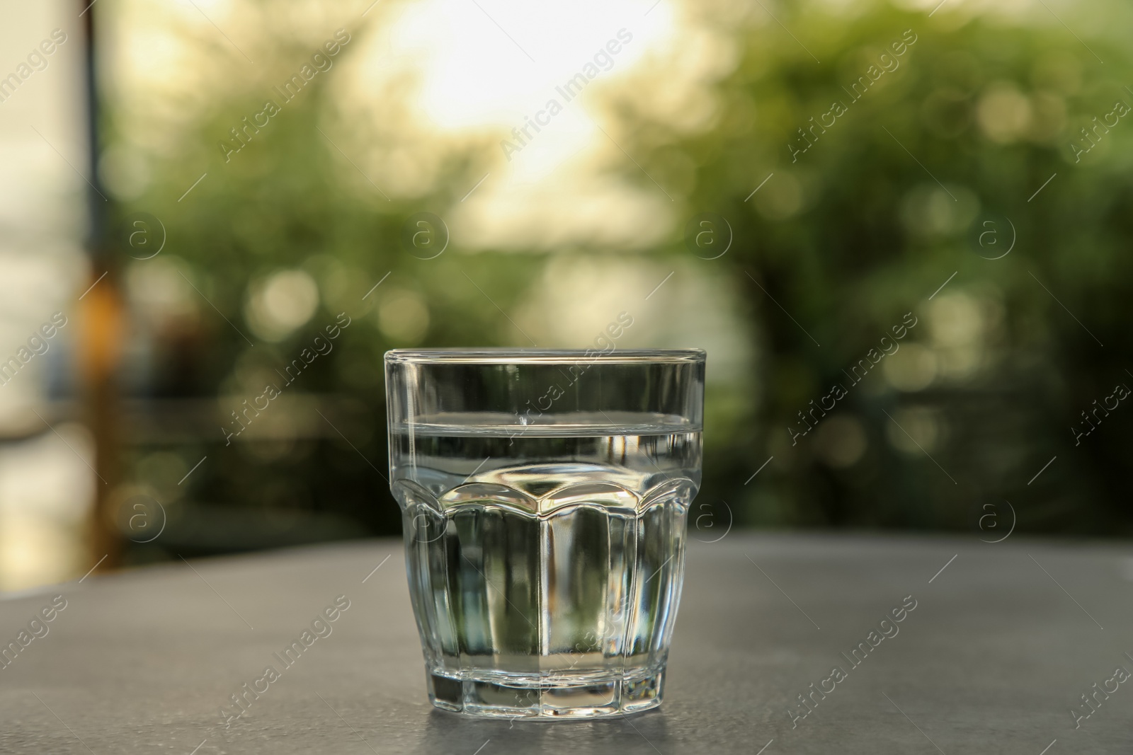 Photo of Glass of fresh water on grey table outdoors