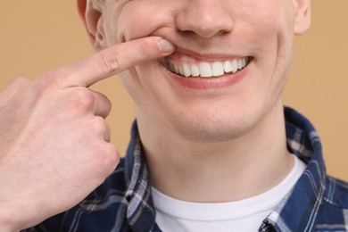 Man showing his clean teeth on beige background, closeup