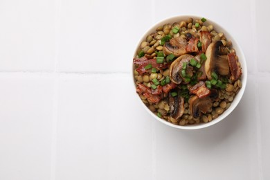Photo of Delicious lentils with bacon and green onion in bowl on white table, top view. Space for text